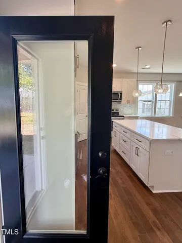 a kitchen with stainless steel appliances granite countertop a refrigerator a sink and white cabinets
