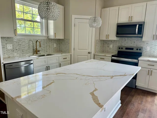 a kitchen with stainless steel appliances a stove microwave and sink