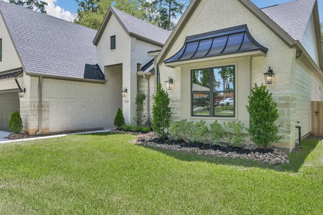a view of a house with brick walls and a yard with plants