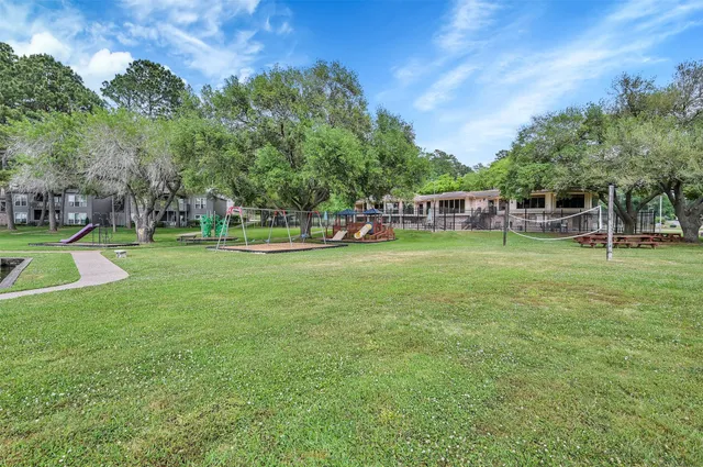 a view of a park with large trees and a wooden fence