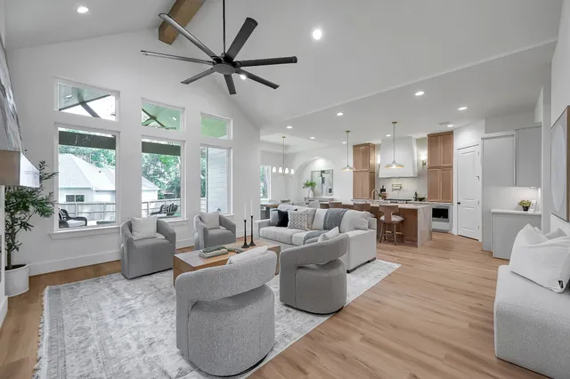 a living room with couches kitchen view and a large window