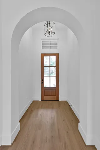 an empty room with wooden floor chandelier and window