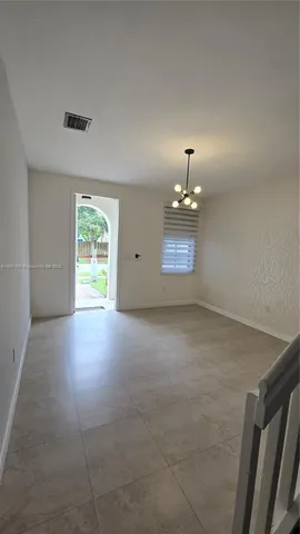 a view of a hallway to room with wooden floor and furniture
