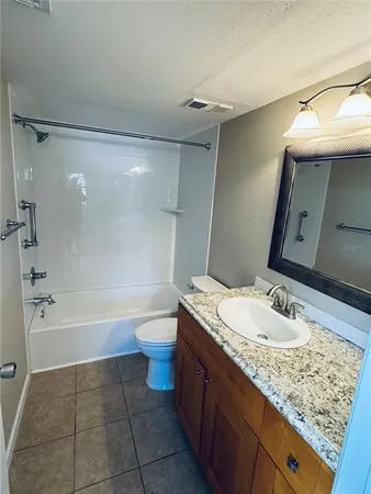 a bathroom with a granite countertop sink a toilet and bathtub