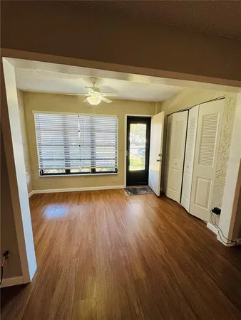 a view of an empty room with wooden floor and a window