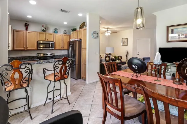 a kitchen with stainless steel appliances a dining table chairs stove and refrigerator