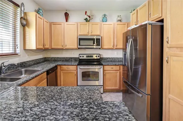 a kitchen with granite countertop a refrigerator stove and sink