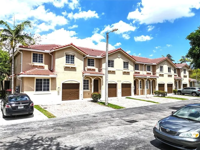 a view of a white house with large windows next to a yard