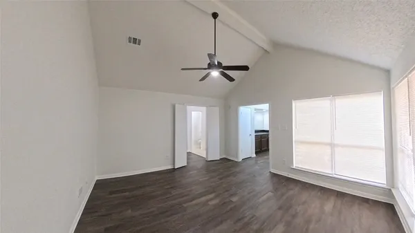 an empty room with wooden floor ceiling fan and windows