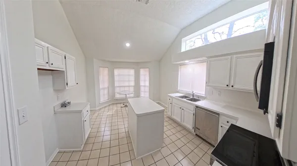 a large white kitchen with a sink a refrigerator and window