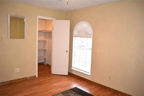 an empty room with wooden floor closet and windows