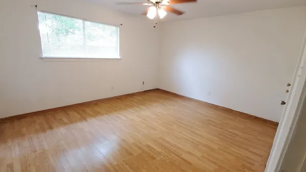 a view of an empty room with a window and wooden floor