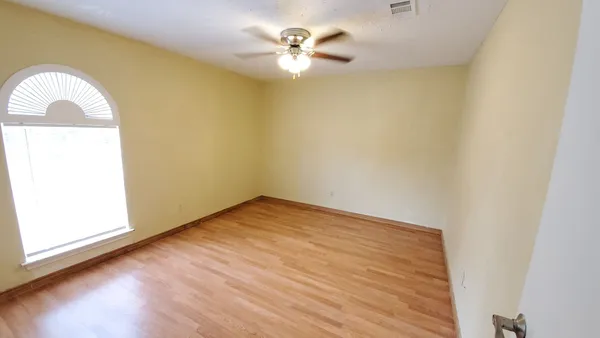 an empty room with a window and a ceiling fan