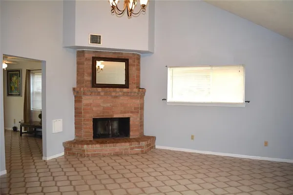 an empty room with windows a fireplace and wooden floor