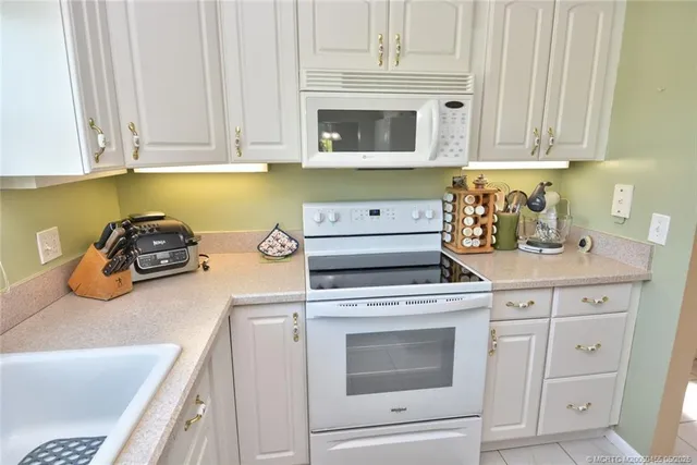 a kitchen with granite countertop white cabinets and white appliances