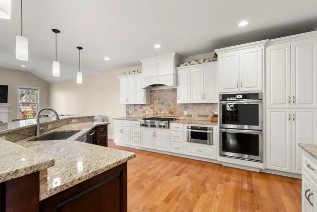 a open kitchen with stainless steel appliances kitchen island granite countertop a table chairs and a refrigerator