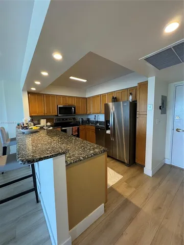 a kitchen with stainless steel appliances granite countertop a refrigerator and a stove