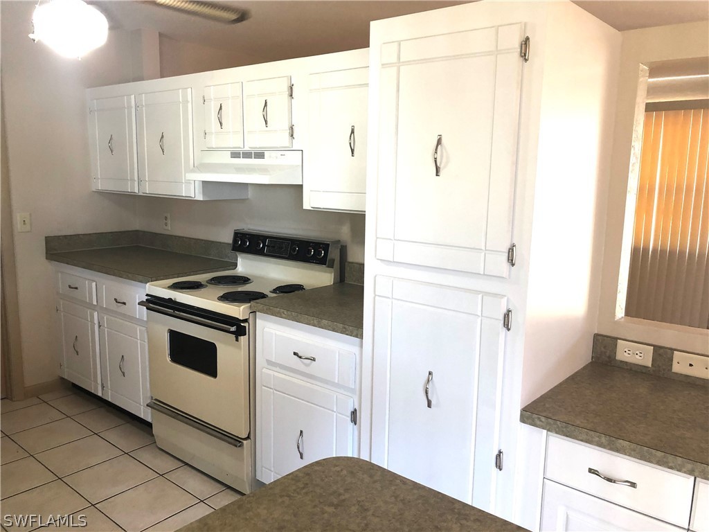 7356 Barragan Road Fort Myers, FL 33967 - Photo 3 of 23 a kitchen with granite countertop white cabinets and white appliances