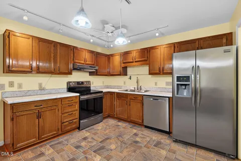 a kitchen with stainless steel appliances granite countertop a sink refrigerator and cabinets
