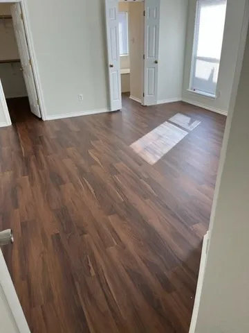 an empty room with wooden floor and windows