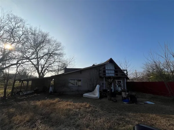 a view of a wooden house with a yard and large trees