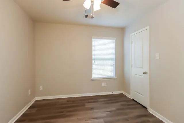 an empty room with wooden floor chandelier fan and window