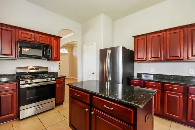 a kitchen with stainless steel appliances granite countertop a stove microwave refrigerator and sink