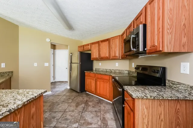a kitchen with stainless steel appliances granite countertop a stove a refrigerator and a microwave oven