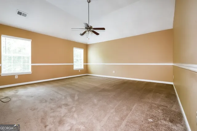 a view of empty room with windows and ceiling fan