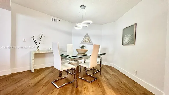 a dining room with wooden floor a chandelier a wooden table and chairs