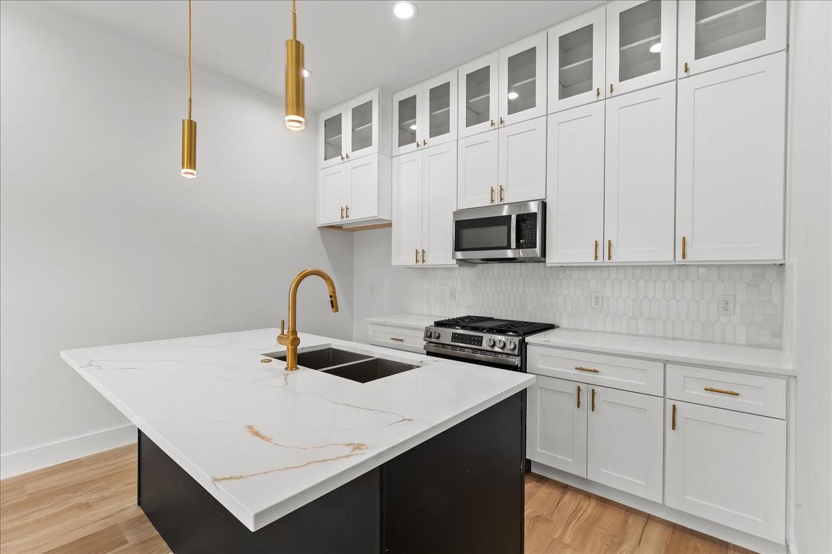8323 Observatory Street, Unit A/B Houston, TX 77088 - Photo 6 of 38 Unit A - Enjoy a sleek, modern kitchen featuring a flat-top stove, stainless steel appliances, elegant gold fixtures, and designer finishes throughout.