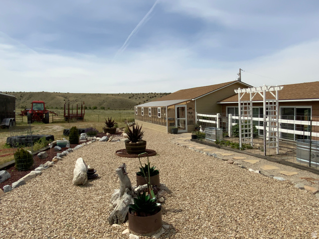 1061 Copper Street Stockton, UT 84071 - Photo 39 of 43 Exterior with a gravel pathway, a white arbor, and raised garden beds