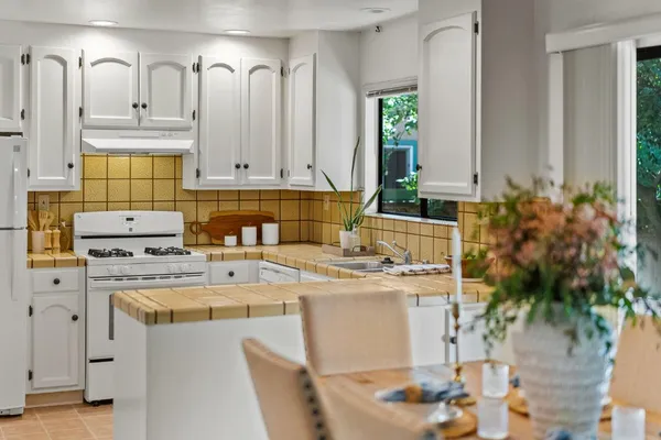 a kitchen with a stove a refrigerator and white cabinets