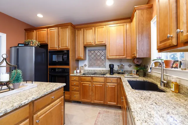 a kitchen with stainless steel appliances granite countertop a sink dishwasher stove refrigerator and cabinets