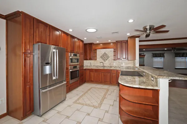 a kitchen with stainless steel appliances granite countertop a sink refrigerator and cabinets