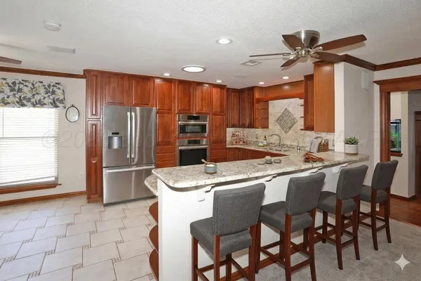 a kitchen with stainless steel appliances kitchen island granite countertop a table chairs and a refrigerator