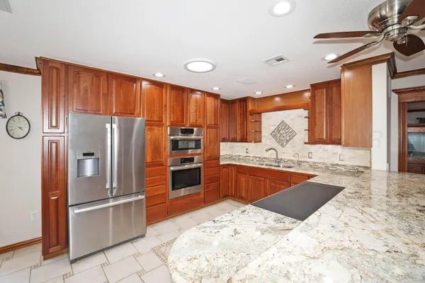 a kitchen with stainless steel appliances kitchen island granite countertop a refrigerator and a sink