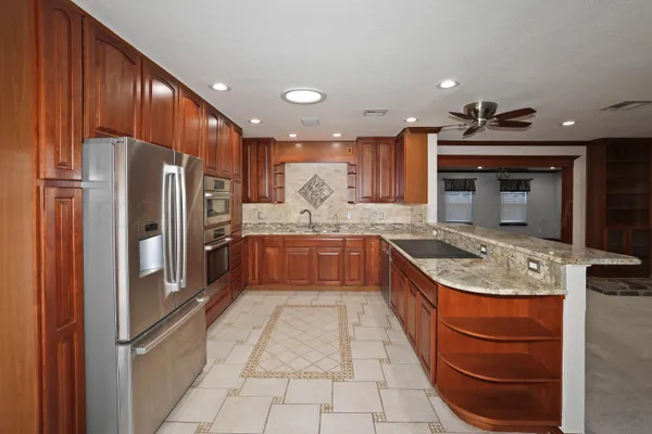 a large kitchen with stainless steel appliances granite countertop a sink a stove and a refrigerator