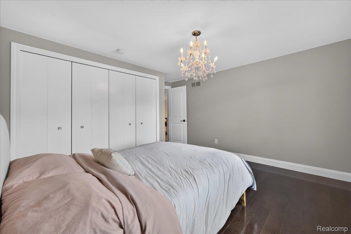 7330 West Gates Street Romeo, MI 48065 - Photo 38 of 73 Spacious room featuring dark wood-finish flooring, a decorative chandelier, and white bifold closet doors