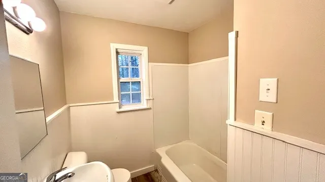 a white toilet sitting next to a bath tub