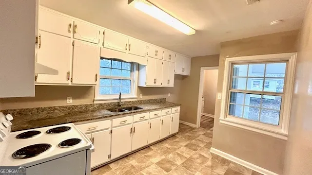 a kitchen with a sink a stove cabinets and a window
