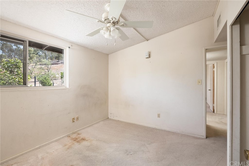 12540 Taunt Place Poway, CA 92064 - Photo 16 of 36 an empty room with a chandelier fan and windows