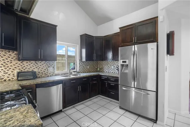a kitchen with stainless steel appliances granite countertop a refrigerator and a stove top oven