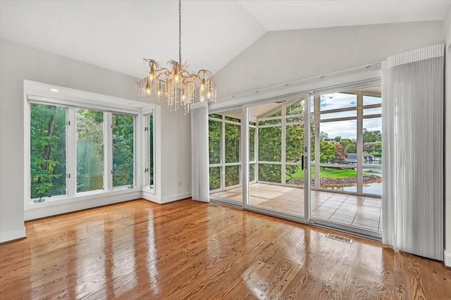 a view of an empty room with wooden floor and a floor to ceiling window