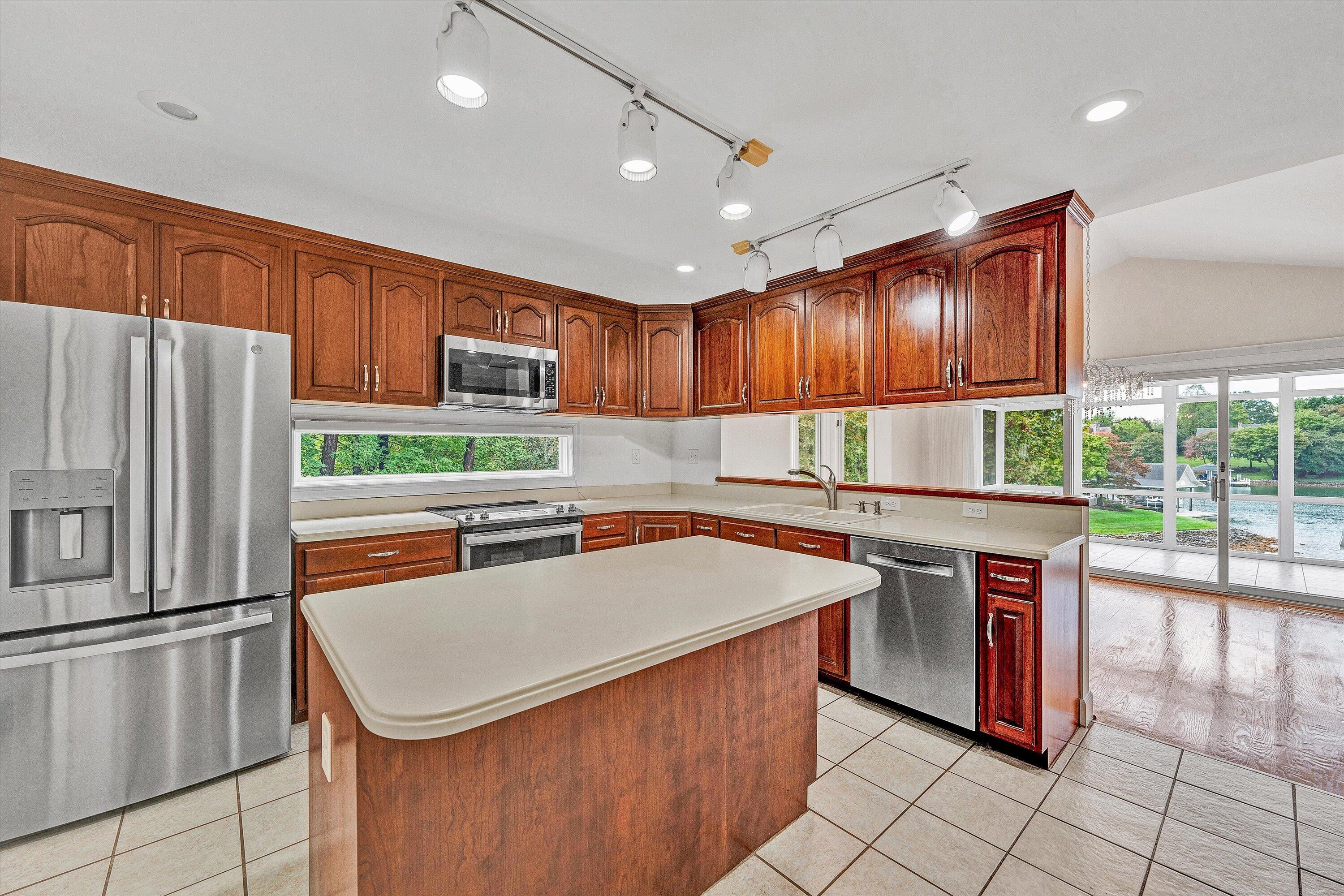 30 Island Green Circle, Unit 22 Penhook, VA 24137 - Photo 18 of 53 a kitchen with stainless steel appliances granite countertop a stove top oven a refrigerator a sink and dishwasher with wooden cabinets