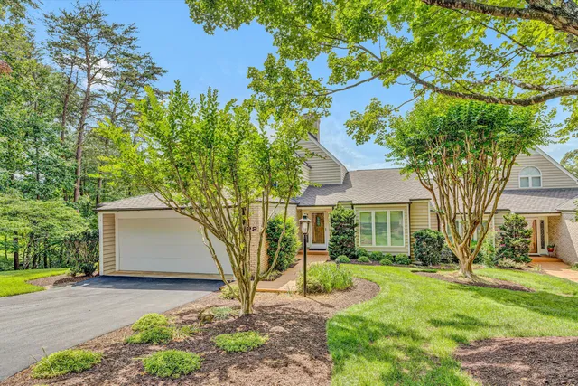 a front view of a house with a garden and trees