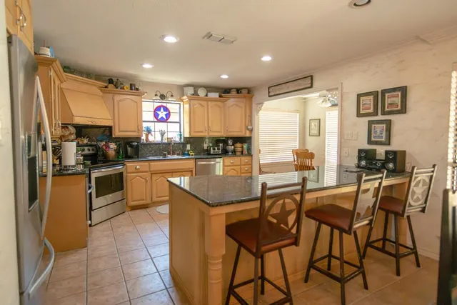 a kitchen with stainless steel appliances kitchen island granite countertop a sink and cabinets