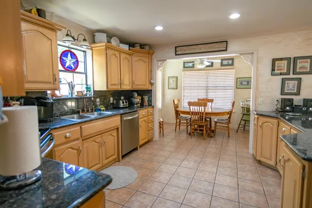 a kitchen with stainless steel appliances granite countertop a sink and a refrigerator