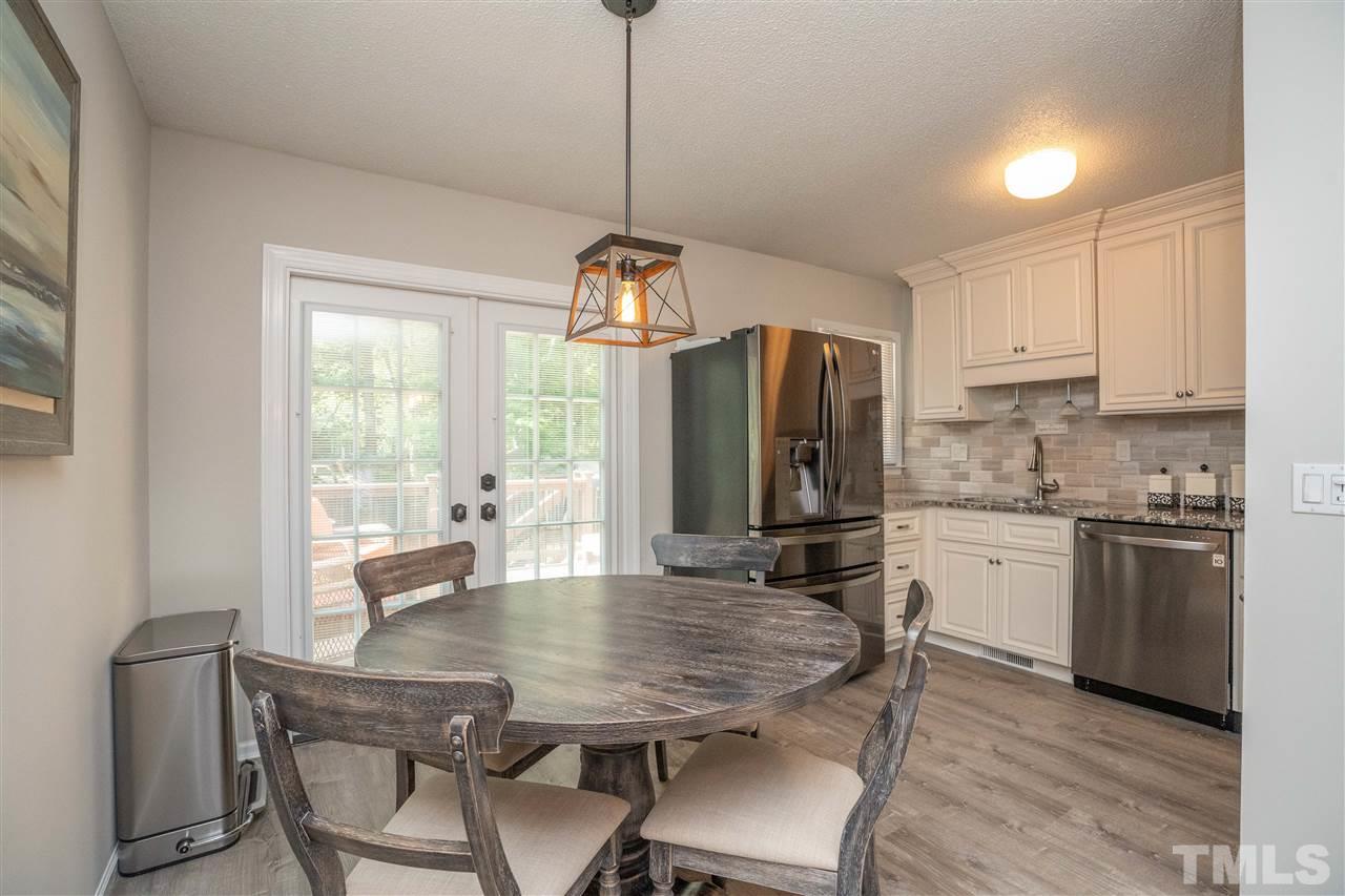 7500 Mine Valley Road Raleigh, NC 27615 - Photo 6 of 25 a kitchen with stainless steel appliances granite countertop a stove a refrigerator a kitchen island a dining table and chairs with wooden floor