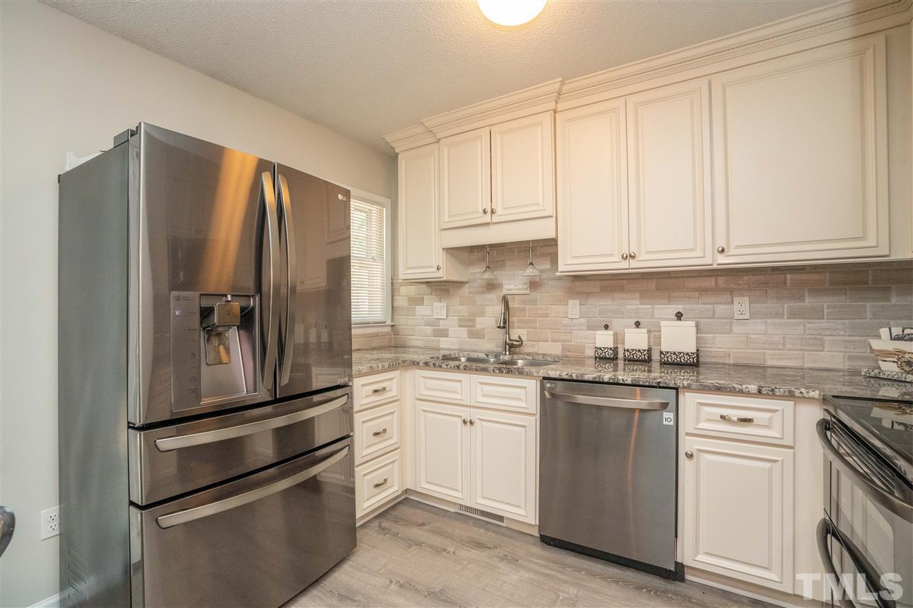 7500 Mine Valley Road Raleigh, NC 27615 - Photo 7 of 25 a kitchen with stainless steel appliances granite countertop a refrigerator sink and white cabinets
